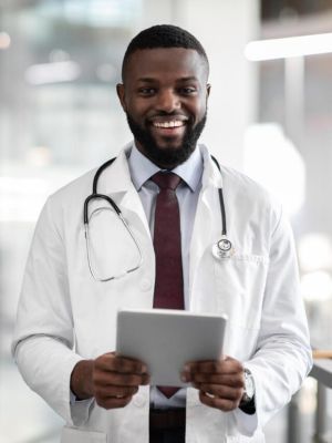 positive-young-black-doctor-holding-digital-tablet-clinic-interior
